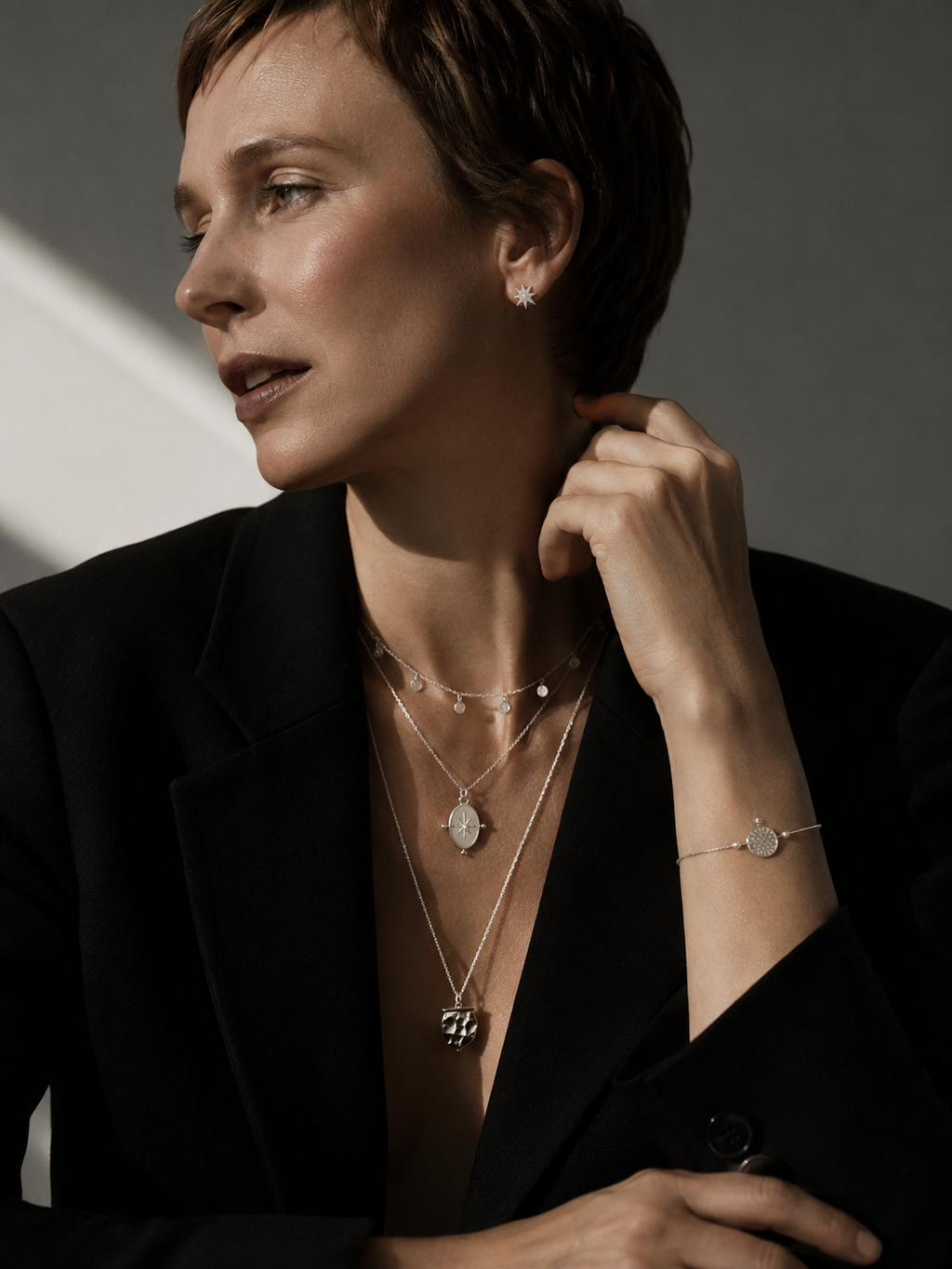Modern Nordic silver jewelry set styled in Scandinavian fashion editorial aesthetic with layered necklaces and silver star earrings.