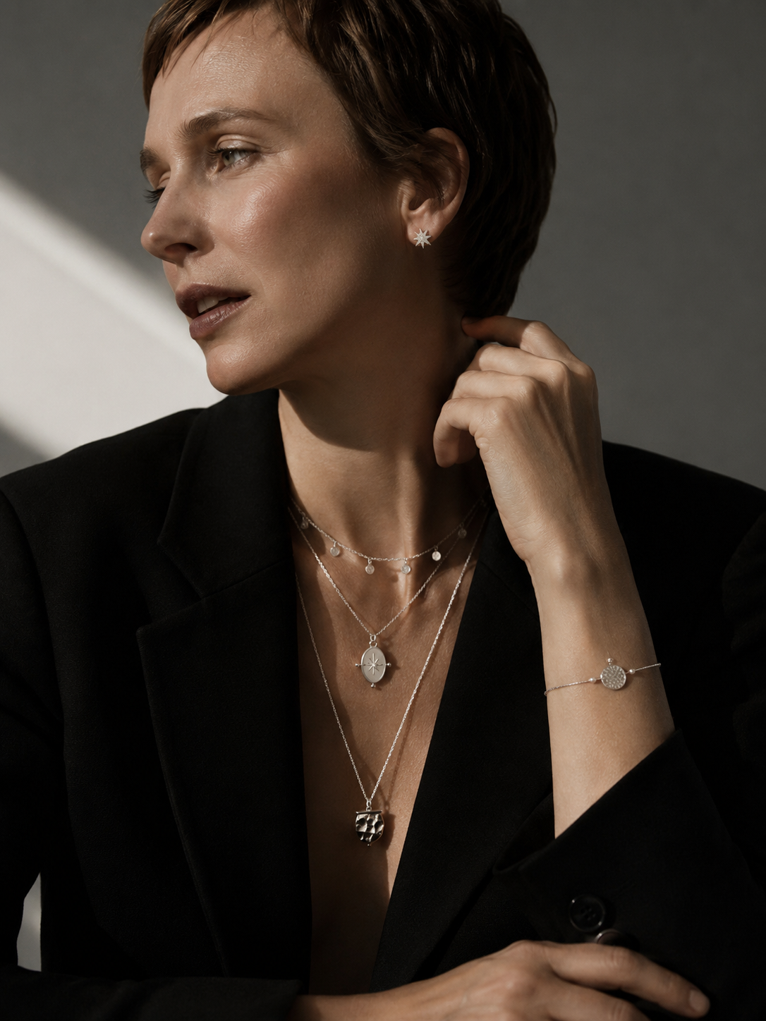 Modern Nordic silver jewelry set styled in Scandinavian fashion editorial aesthetic with layered necklaces and silver star earrings.