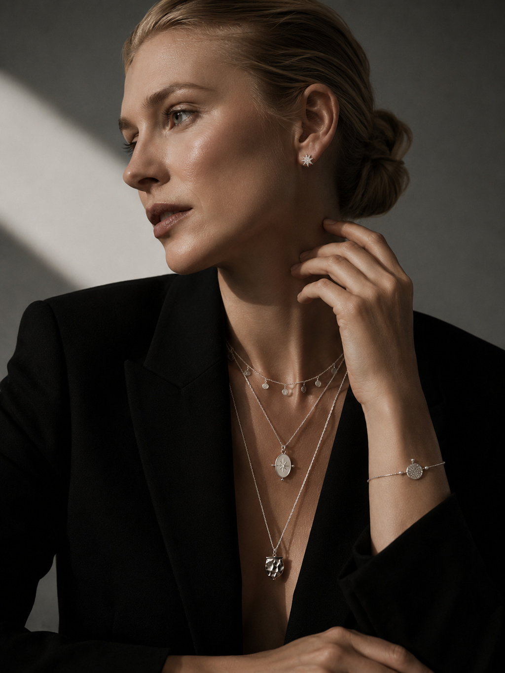 Woman wearing layered silver necklaces, silver star stud earrings and minimalist Nordic jewelry styling in a moody Copenhagen-inspired editorial portrait.
